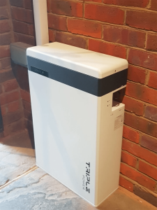 A Triple Power battery storage device on a brick wall